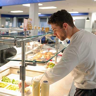 a student serves food from a buffet in the dining hall